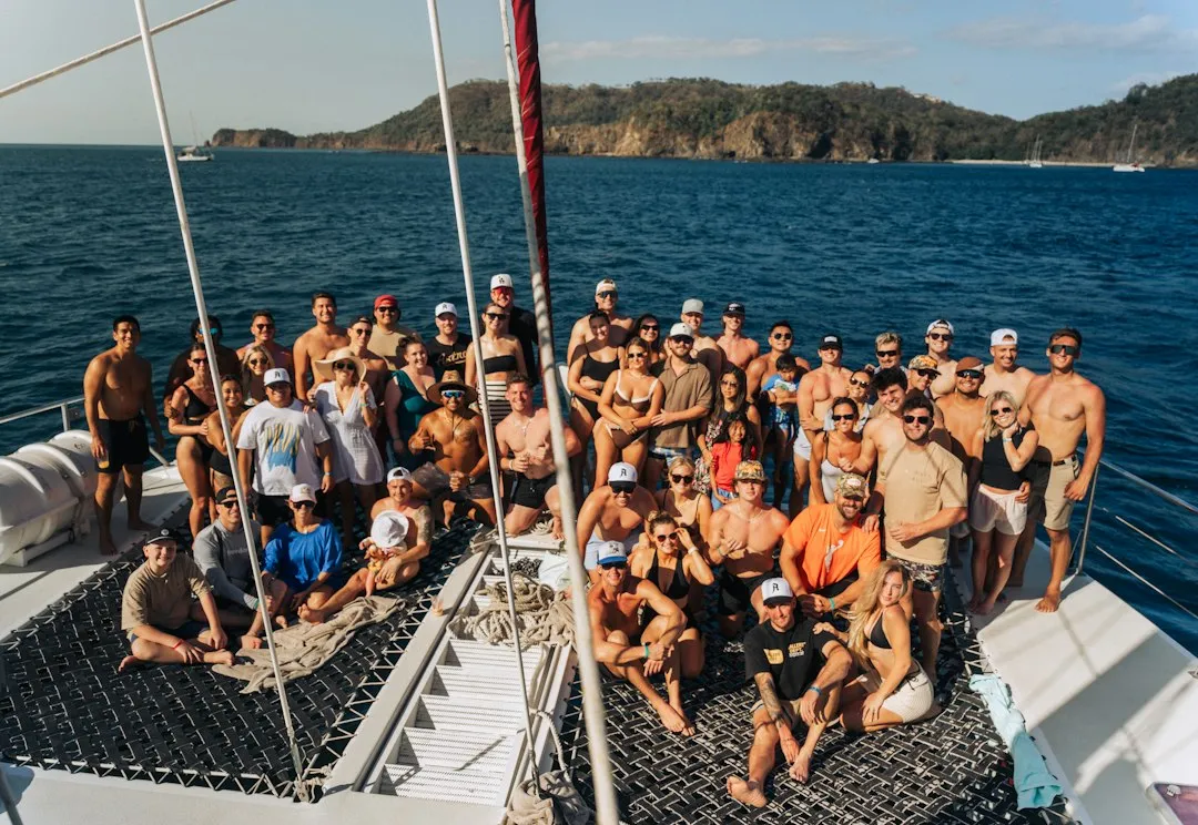 Large group of friends posing on a catamaran deck at sea